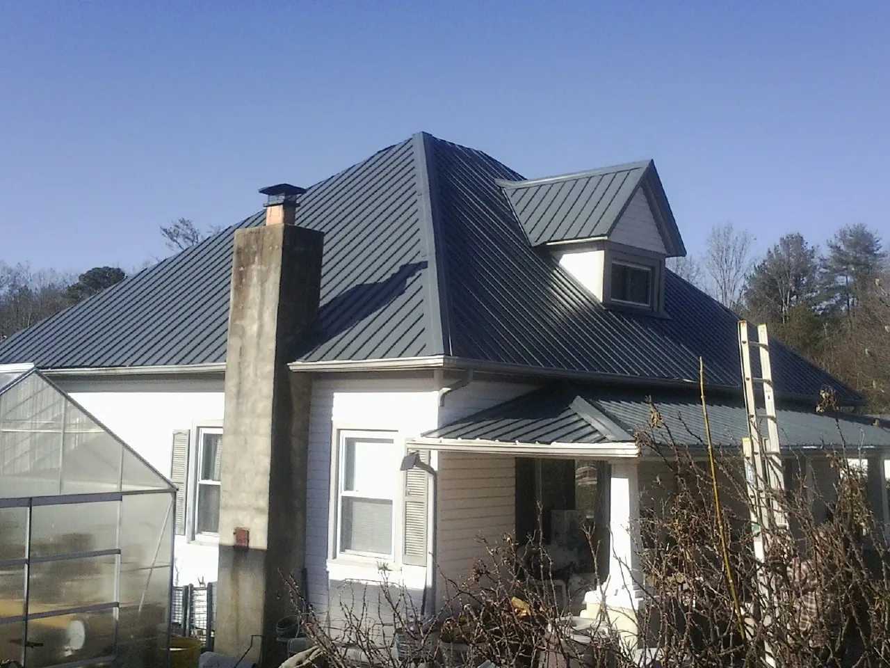 Dark blue standing seam metal roof on a white farmhouse with dormer — Slate & Tile Roof Repair by Roofing Brothers in Califon