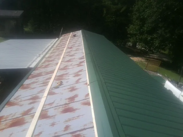 Old rusted panels beside newly installed green metal roofing — Wind Damage Roof Repair by Roofing Brothers in Califon