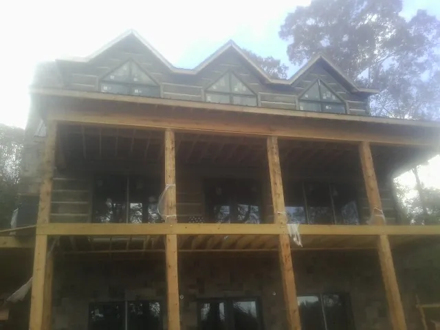 Dormers and porch framing on a large log home under construction — Roof Coating work by our crew in Califon