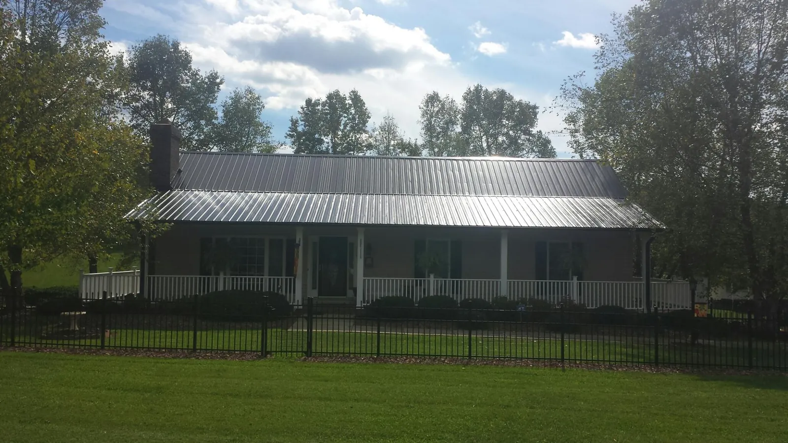 Gray metal roof on a brick ranch with a full width front porch — Gutter Guard Installation work by our crew in Califon