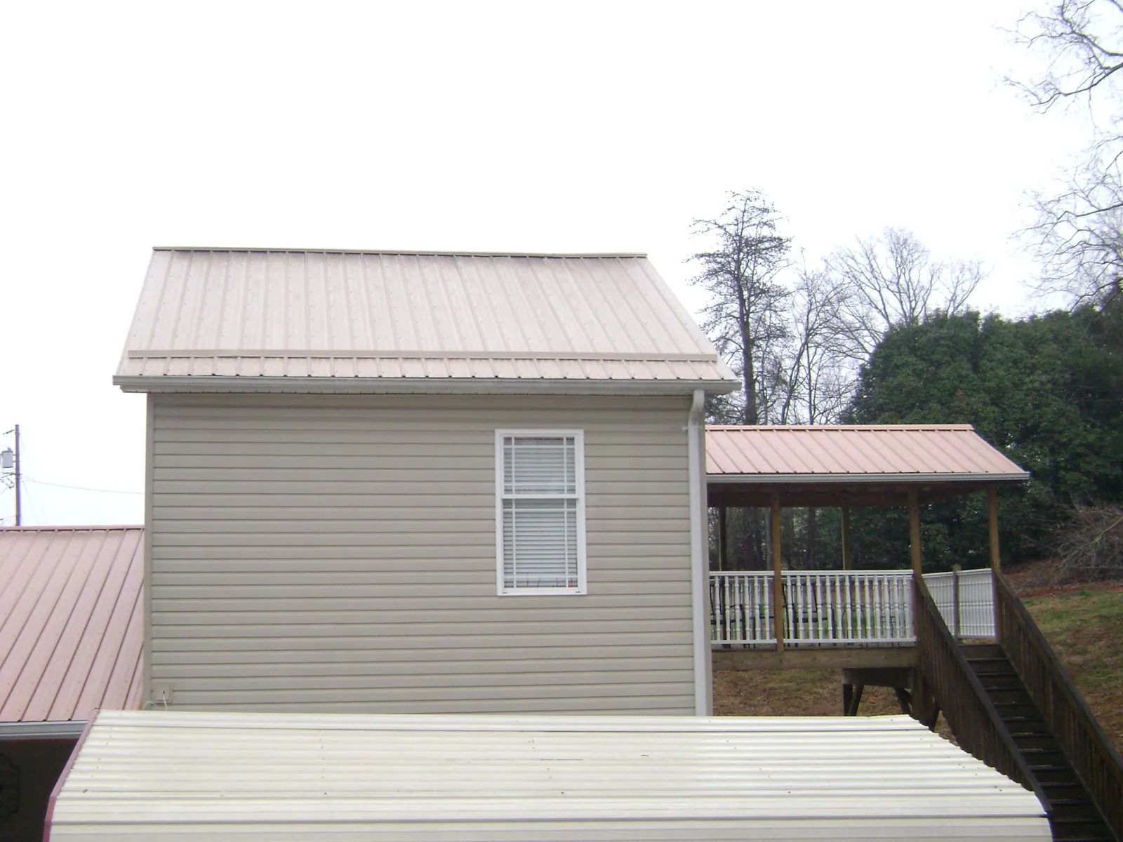 Tan metal roofs on a two story addition and attached porch, from a Roof Replacement job in Califon