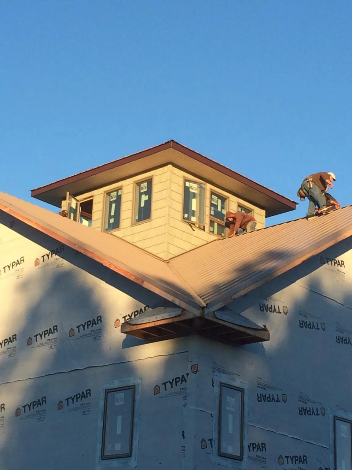 Roofers working around a rooftop cupola on a new metal roof at sunset — Roof Waterproofing in Califon by Roofing Brothers